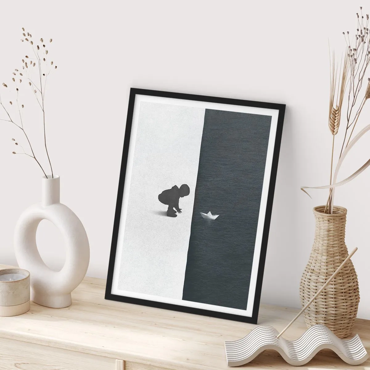 Plakat i sort ramme - Et barn læner sig ud over vandet med en papirbåd - 50x70cm - Stor ekspedition - Moderne vægdekoration til stue og soveværelse ARTTOR