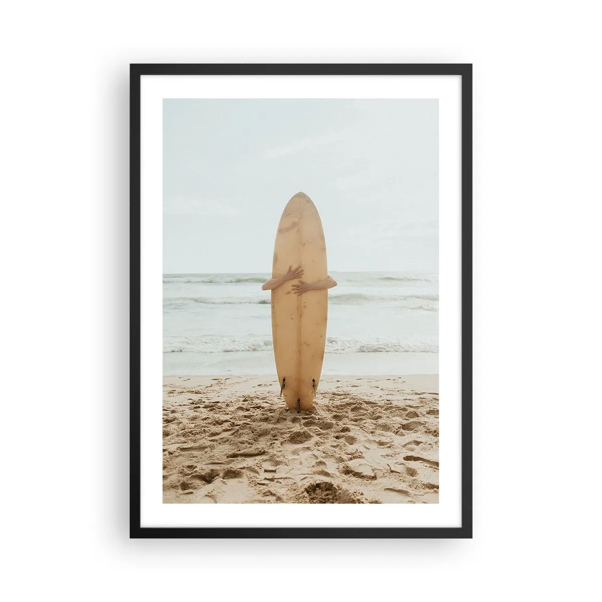 Plakat i sort ramme - En person, der holder et surfbræt på en strand med udsigt over havet. - 50x70cm - Af kærlighed til bølgerne - Moderne vægdekoration til stue og soveværelse ARTTOR